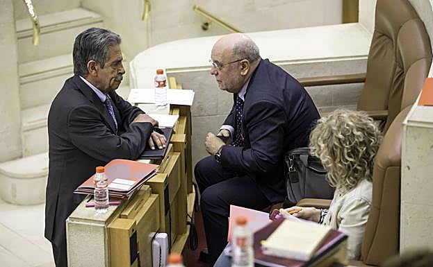 Juan José Sota y Miguel Ángel Revilla conversan en un receso de un pleno en el Parlamento. 