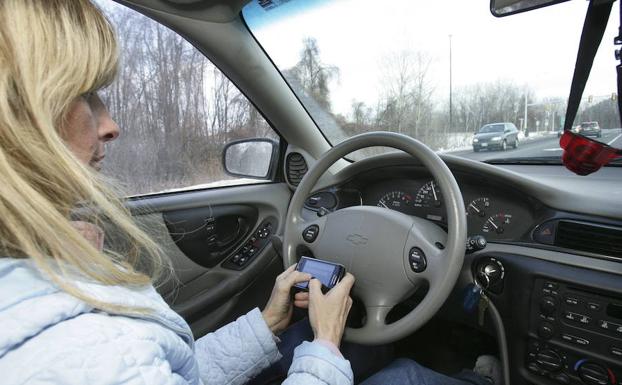 Mujer envía un mensaje desde su teléfono móvil mientras conduce.