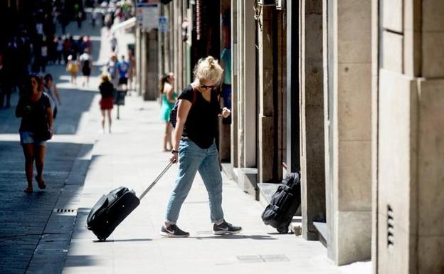 Varios turistas entran en un portal particular para pasar sus vacaciones en un alojamiento turístico. 