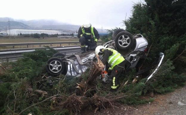 Los bomberos intentan sacar a las personas accidentadas del interior del coche.