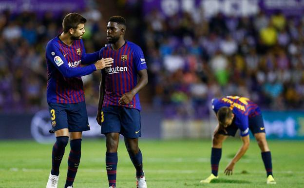 Gerard Piqué habla con Umtiti, mientras Jordi Alba coloca el césped. 