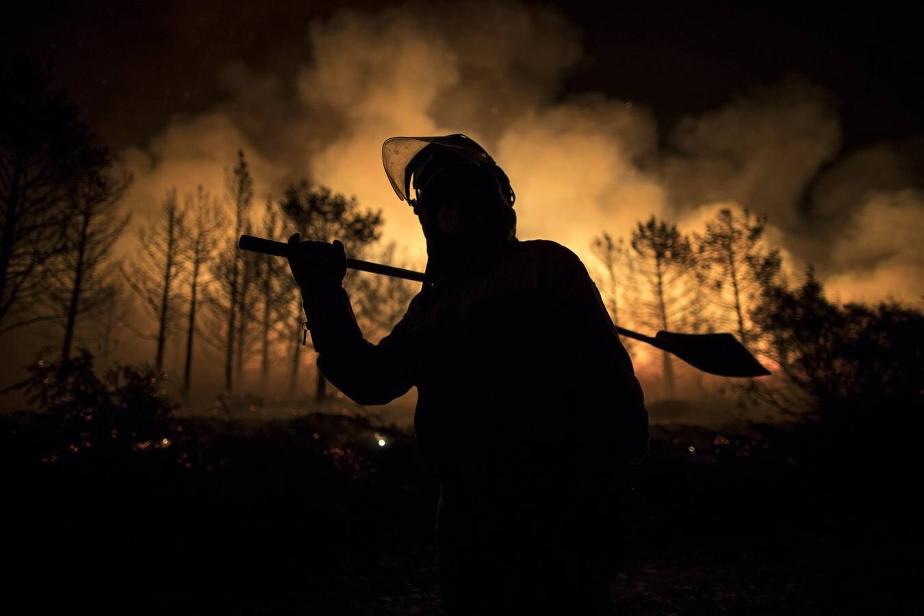 Un brigadista intenta sofocar un fuego de madrugada en A Gudiña durante los incendios que arrasaron Galicia. 