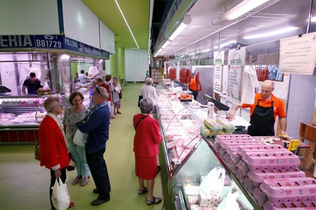 Los puestos tradicionales de la Plaza de Abastos atienden al público, mientras los nuevos, al fondo, todavía permanecen vacíos. 