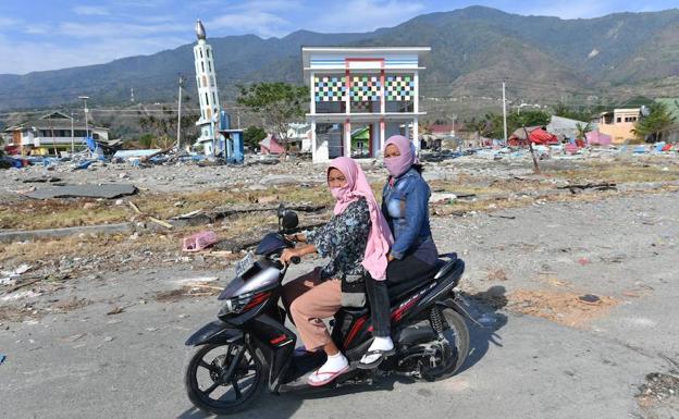 Dos mujeres pasan con su motocicleta por Palu. 