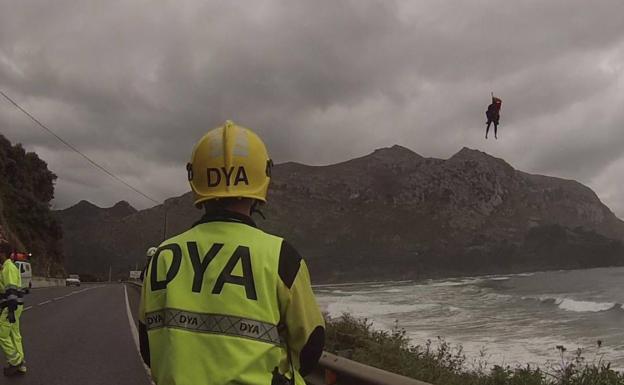 Un sanitario de la DYA Cantabria observa como el helicóptero sube al surfista.