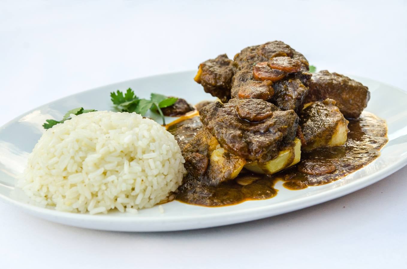 Imagen secundaria 1 - Arriba, ají de gallina. Abajo, seco de chuletillas de cordero a la peruana y el chef Edinson Vílchez.