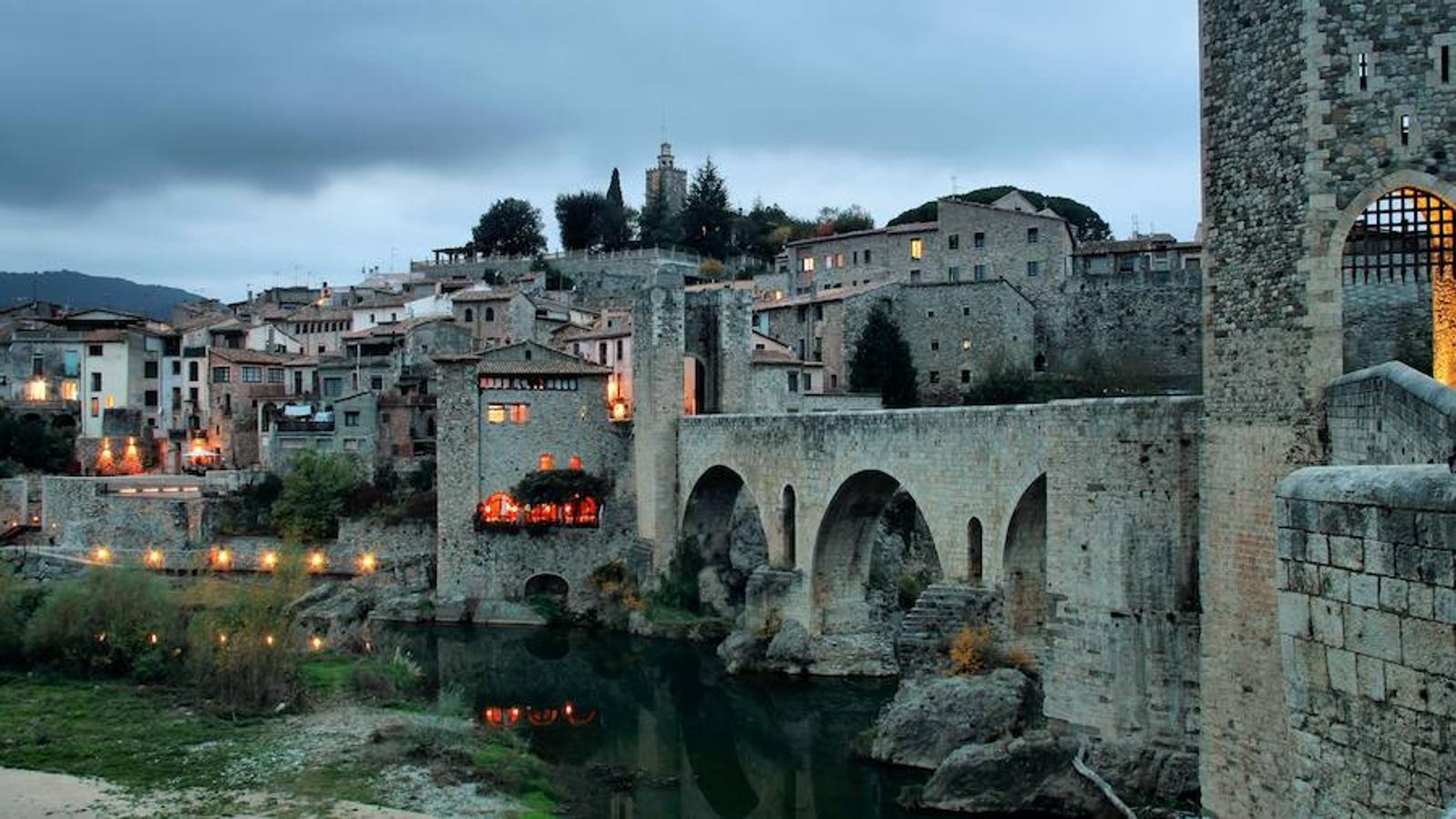Besalú (Girona) | Una fortaleza medieval entre dos ríos, cerca de la frontera con Francia, donde el tiempo parece haberse detenido por completo. Su imagen es propia de los cuentos de hadas: adentrado en plena montaña, lleno de vegetación, en perfecto estado de conservación y hasta con un castillo. El pueblo fue formándose en torno a la fortaleza y hoy es toda una auténtica postal de siglos pasados. 