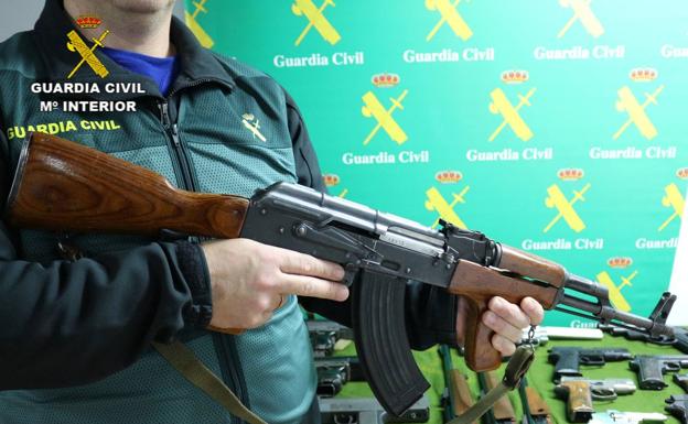 Un agente sostiene uno de los fusiles fusil AK47 incautados.