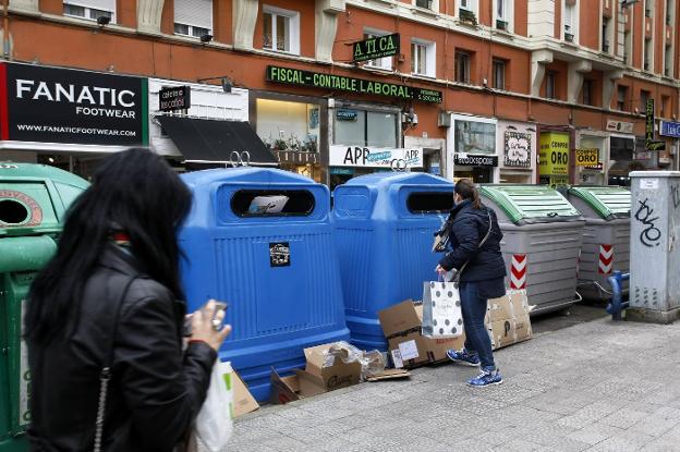 Una mujer deposita cartón en uno de los contenedores ubicado en el centro de Torrelavega. 