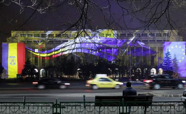 Un hombre observa la engalanada fachada del Palacio Victoria de Bucarest. 