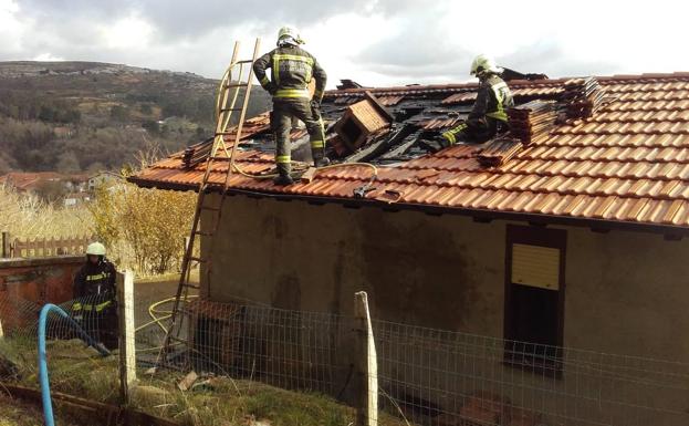 Dos bomberos en el tejado incendiado.