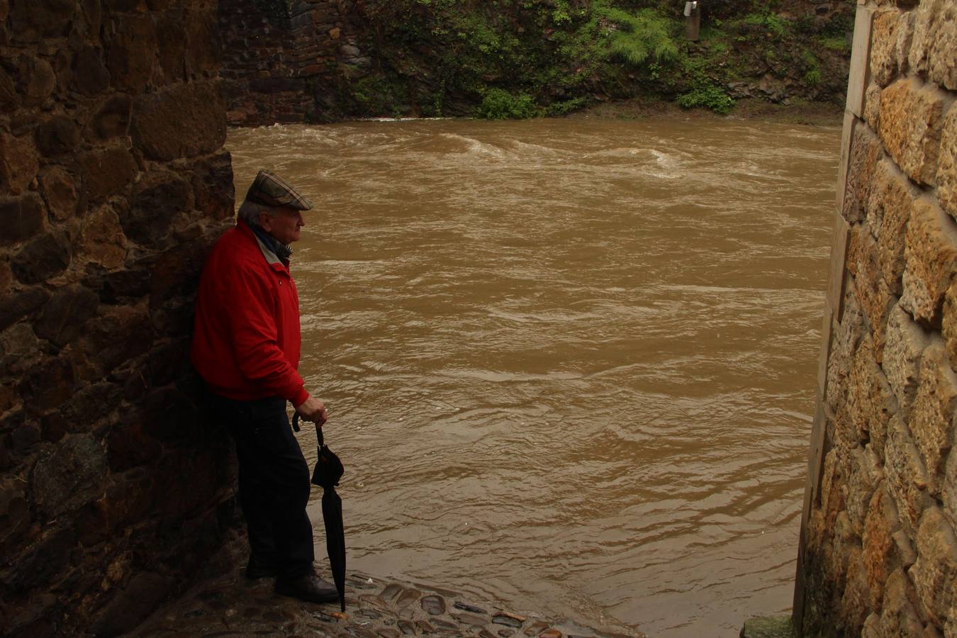 Un vecino de Potes contempla la crecida del río junto al puente de San Cayetano en Potes