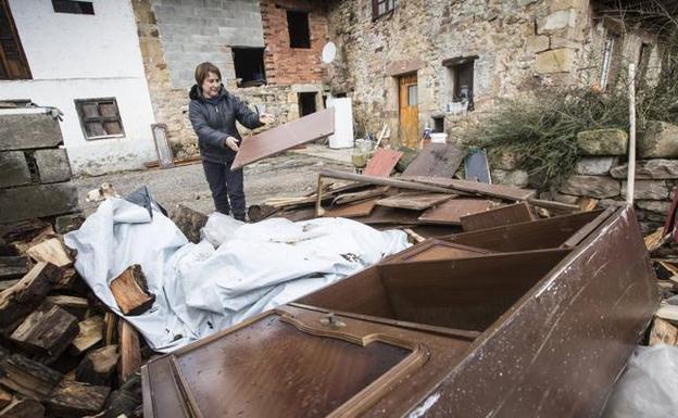 Purificación López tira al montón donde tiene la leña lo que eran los muebles de su salón. Al fondo, también en la calle, tiene la nevera.