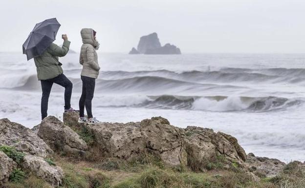 Dos personas observan el fuerte oleaje frente a la costa de Liencres. 