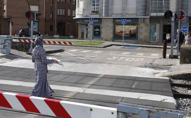 Una mujer cruza el paso a nivel saltándose las barreras de seguridad.