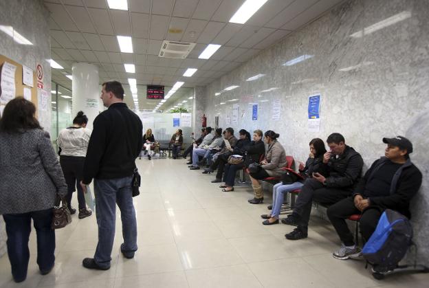 Varias personas esperan turno en una oficina de empleo. 