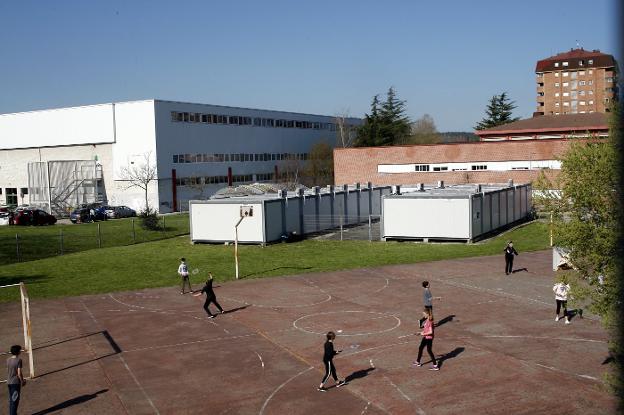 Alumnos del IES Zapatón juegan en la pista deportiva junto a algunos de los barracones que palían la falta de espacio en el centro educativo. 