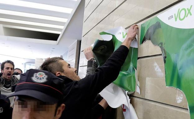 Un simpatizante de la izquierda abertzale arranca un cartel de Vox durante el mitin del partido de Abascal en San Sebastián.