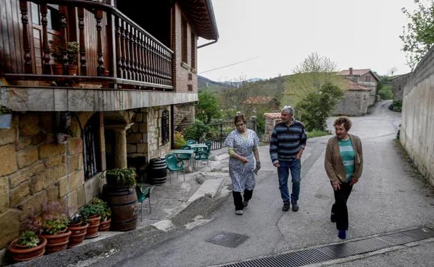 MªCarmen Marcano (izda.) pasea con sus vecinos, los hermanos Alejandro y Carmen Marcano, ambos jubilados, frente al bar que regenta en Collado de Cieza. :