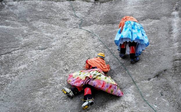 Dos cholitas escalando una pared.