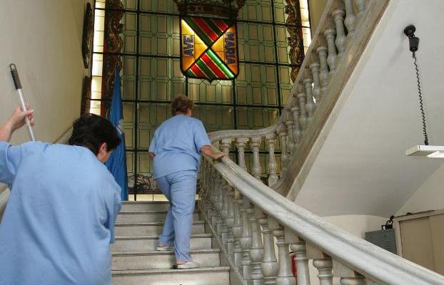 Dos operarias limpian la escalera principal del Palacio municipal de Torrelavega.