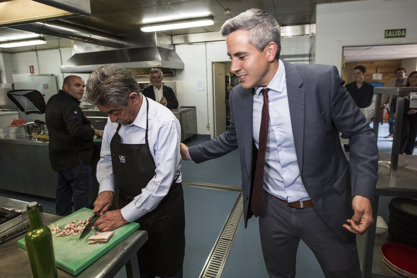 Pablo Zuloaga saluda a Revilla mientras el presidente corta la panceta para el revuelto de perrechicos.