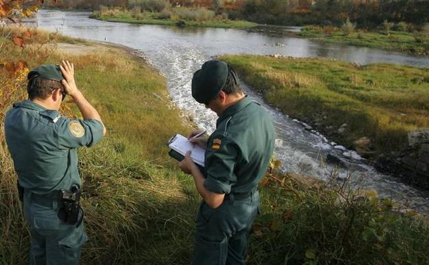 Dos guardias civiles toman notas sobre vertidos de Sniace al río Saja-Besaya hace varios años.