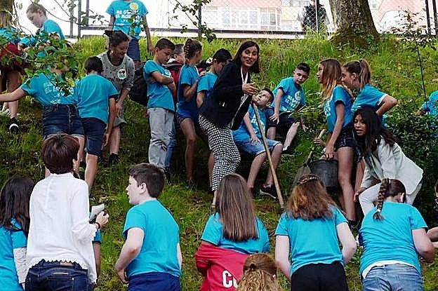 Los alumnos de Manuel Llano ayudan a Gema Igual a plantar un castaño que simboliza su compromiso con el medio ambiente. 