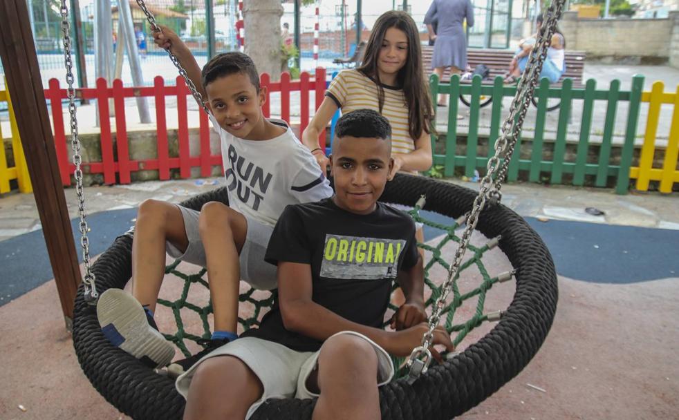 Sudani, con una camiseta negra, posa en un parque cercano a su casa de acogida con sus primos españoles, Denis y Valeria. 