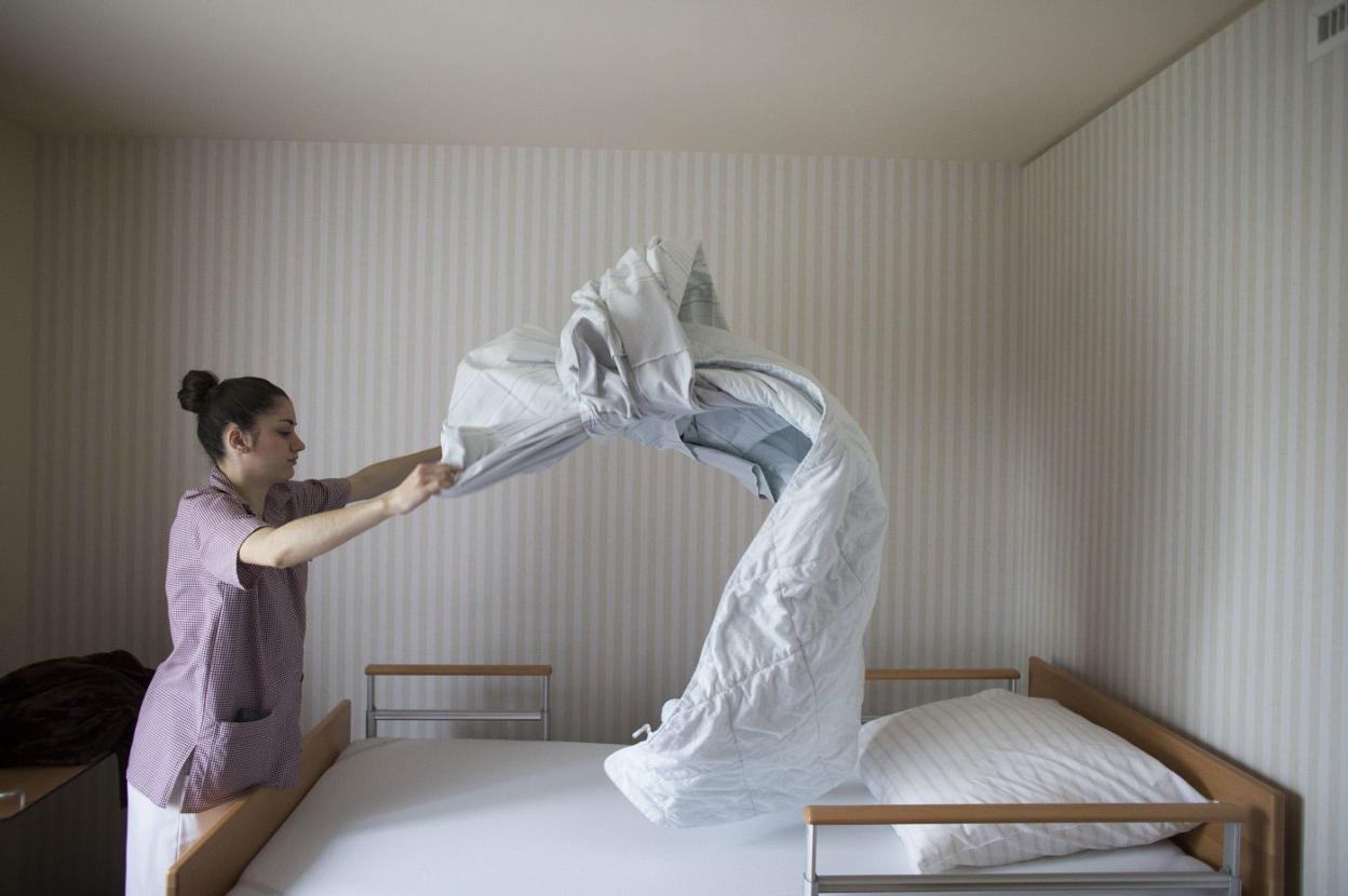 Una mujer trabaja realizando un servicio de habitación en una residencia. :: reuters
