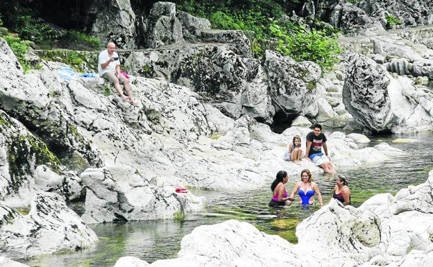 Un grupo de bañistas se refresca un poco más abajo de la presa de Puente Viesgo.