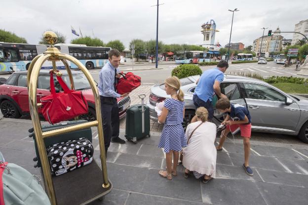 Personal del Gran Hotel Sardinero ayuda a una familia a sacar las maletas del coche, ayer, tras su llegada a Santander. 