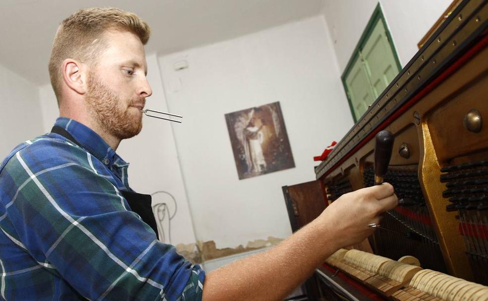 Daniel Chiprian, con el diapasón en la boca, afina un piano de 103 años.