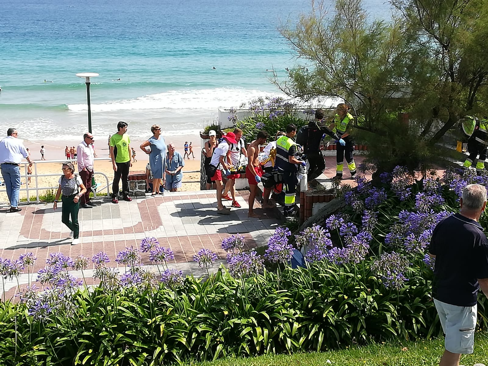 El hombre fallecido es evacuado de la playa por los socorristas de Cruz Roja y los sanitarios del 061