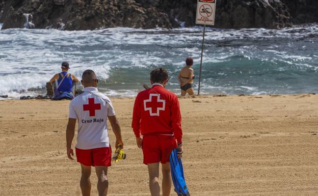 Los socorristas de la playa de San Juan de la Canal, en Bezana, se acercan a la orilla para avisar de la bandera roja a los bañistas.