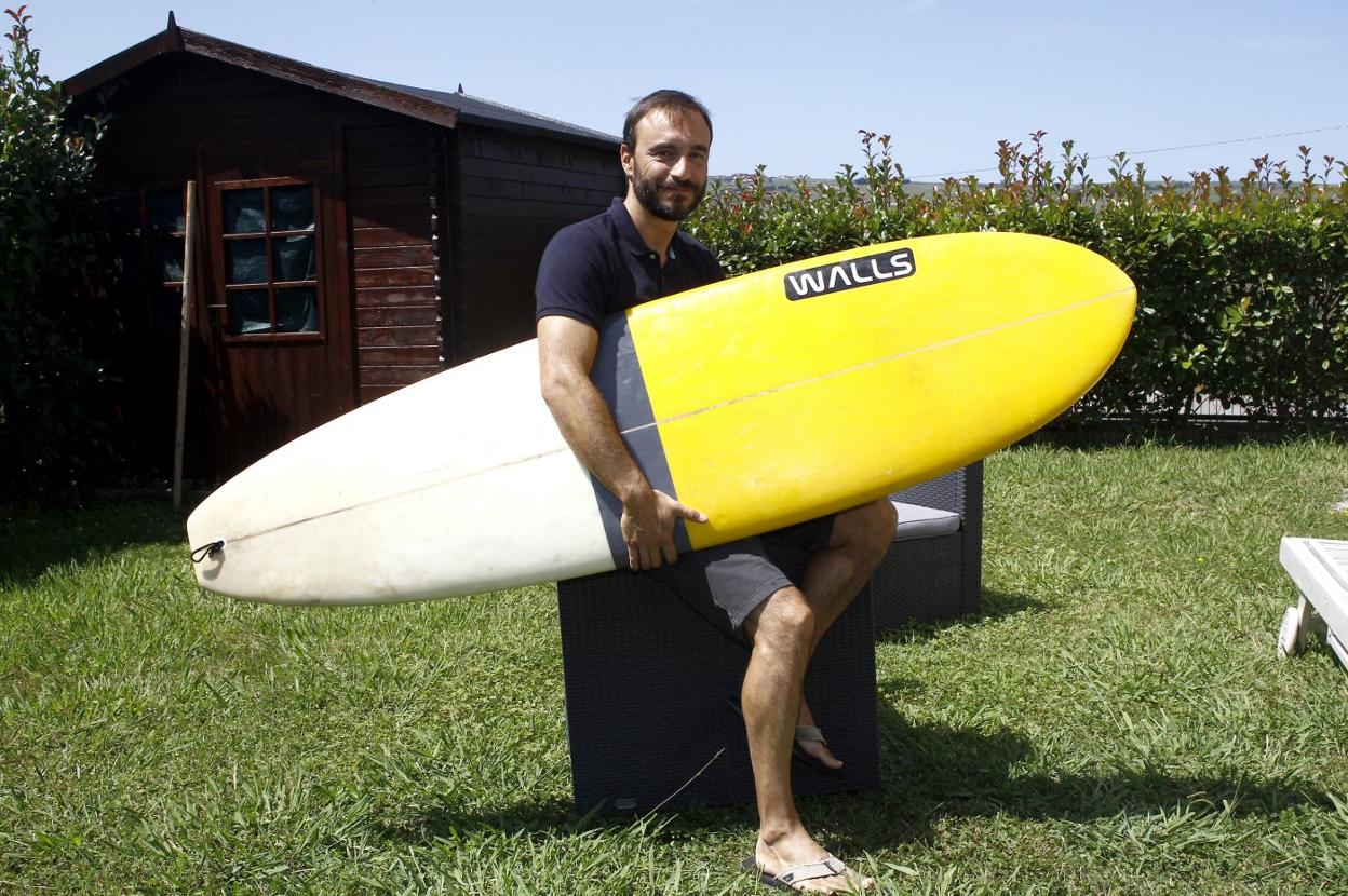 Fernando Oreña, voluntario, con una tabla de surf en la playa de Suances 