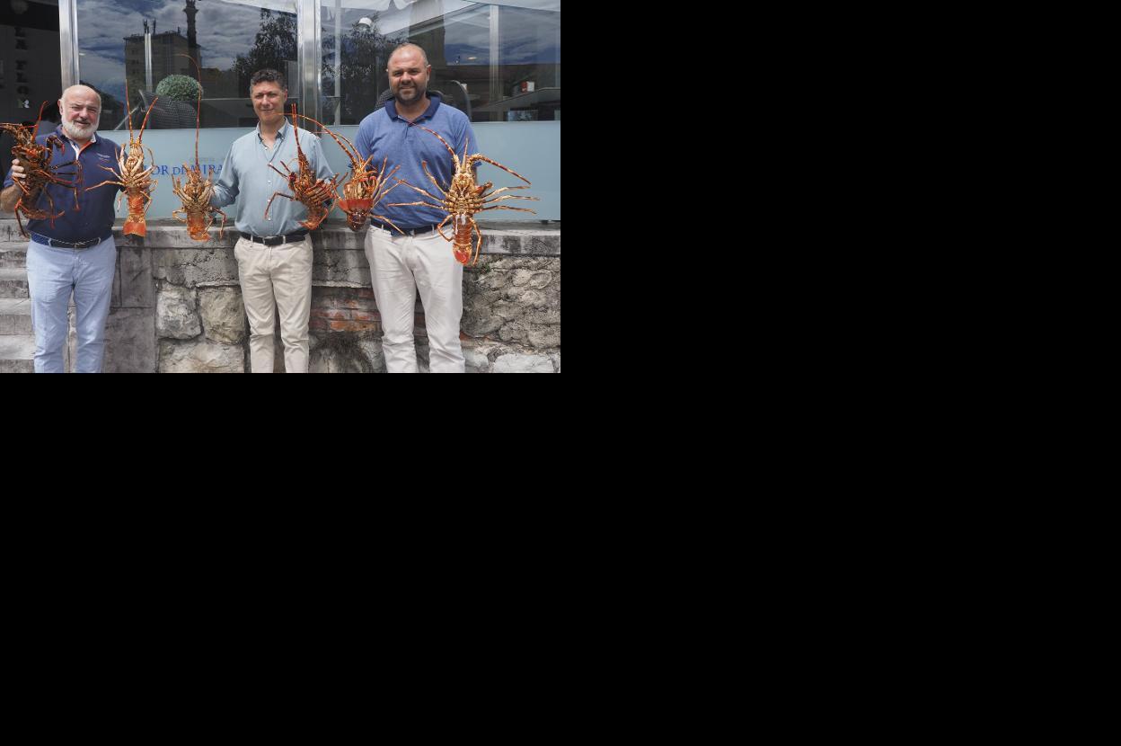 Ángel Cuartas, Cristian Peramato y Miguel Ángel Cuartas sostienen sendas langostas en la terraza del restaurante. 