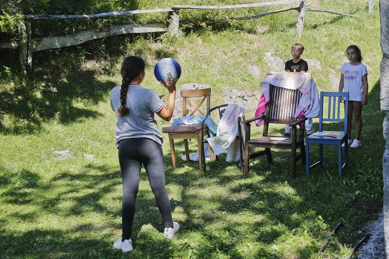 Ángela, Francisco y Lola juegan al voleibol. Utilizan las sillas como red.