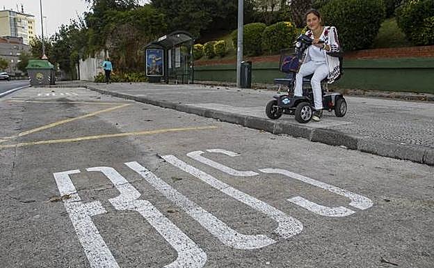 Lola González-Pinto, ante una parada de autobús, con su motosilla. 