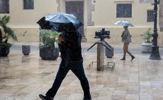 Un hombre camina bajo la lluvia.