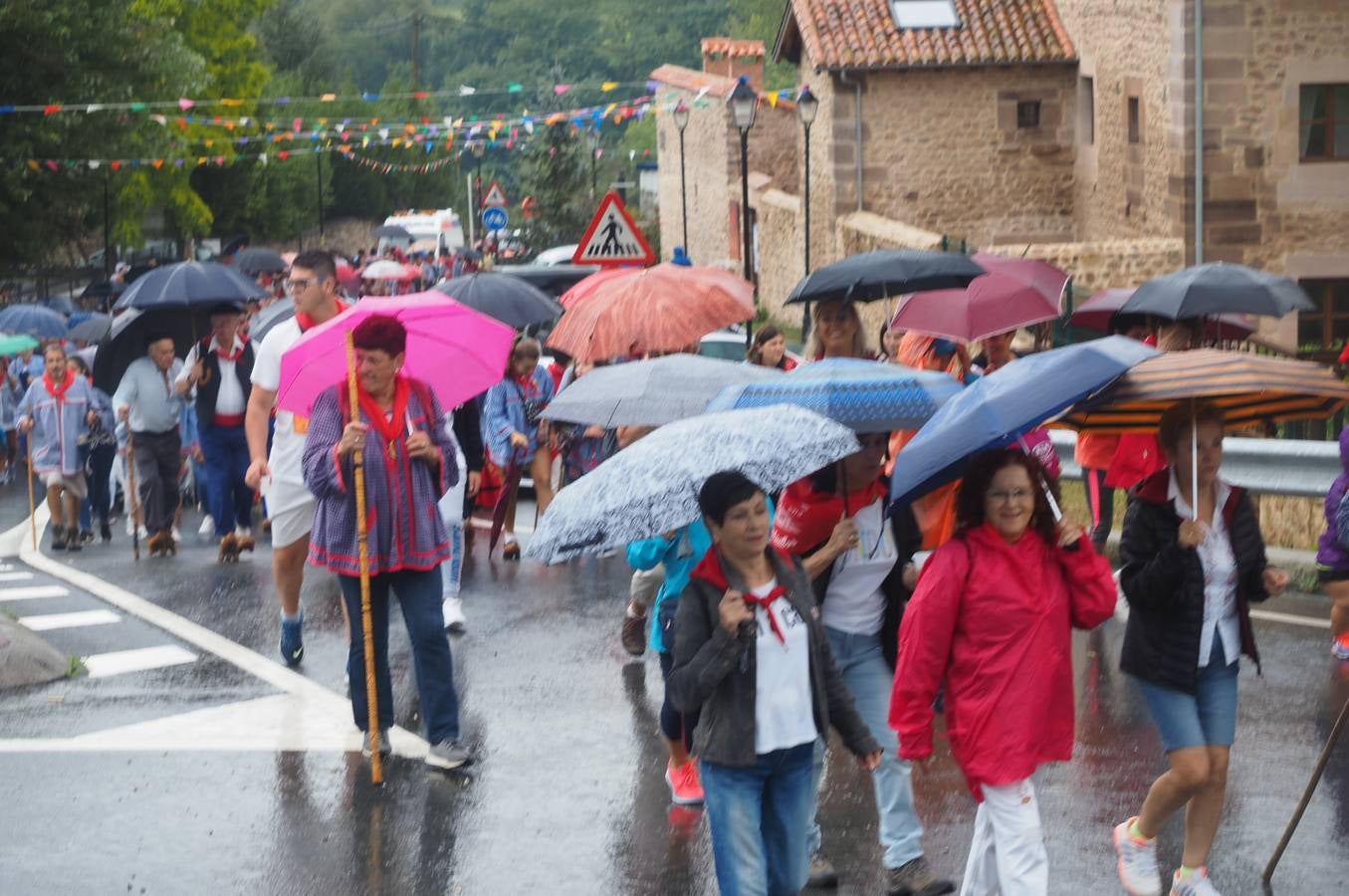 Los vecinos de Cartes tuvieron que sacar los paraguas para participar en el 'Día de las albarcas', caminando bajo la lluvia hasta Cohicillos