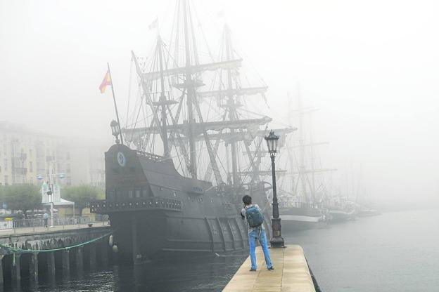 Un joven fotografía el galeón 'Andalucía', cubierto por la niebla.