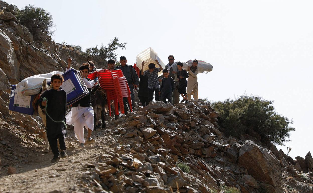Varias personas cargan con material electoral que se transportará a centros de voto no accesibles por carretera.