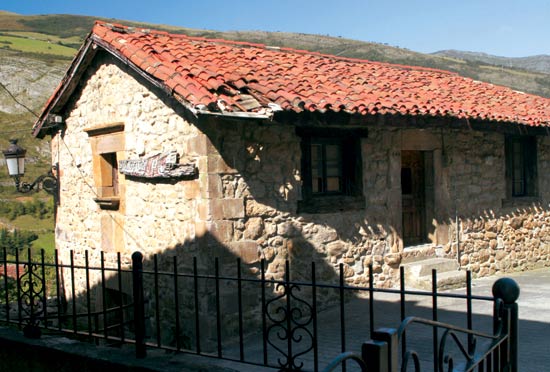 Imagen secundaria 1 - Casona de Tudanca, uno de los escenarios de la novela perediana de Peñas Arriba y morada veraniega de José María de Cossío. Antigua escuela de Tudanca, hoy dedicada a biblioteca. Escudo de la casa de La Herrán, del siglo XVII.