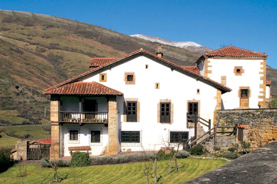 Imagen principal - Casona de Tudanca, uno de los escenarios de la novela perediana de Peñas Arriba y morada veraniega de José María de Cossío. Antigua escuela de Tudanca, hoy dedicada a biblioteca. Escudo de la casa de La Herrán, del siglo XVII.