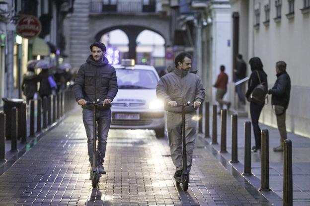 Dos usuarios se mueven en patinete por el centro de Santander.