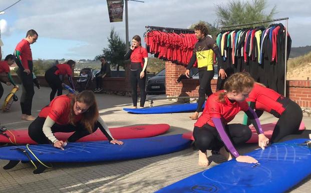 Galería. Tres chicas revisan sus tablas en Noja. :