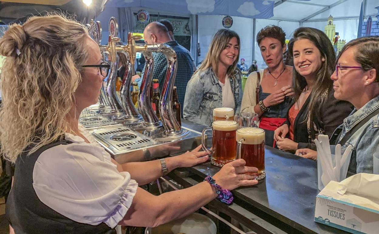 Cuatro mujeres toman unas cervezas en uno de los puestos instalados en la carpa del festival