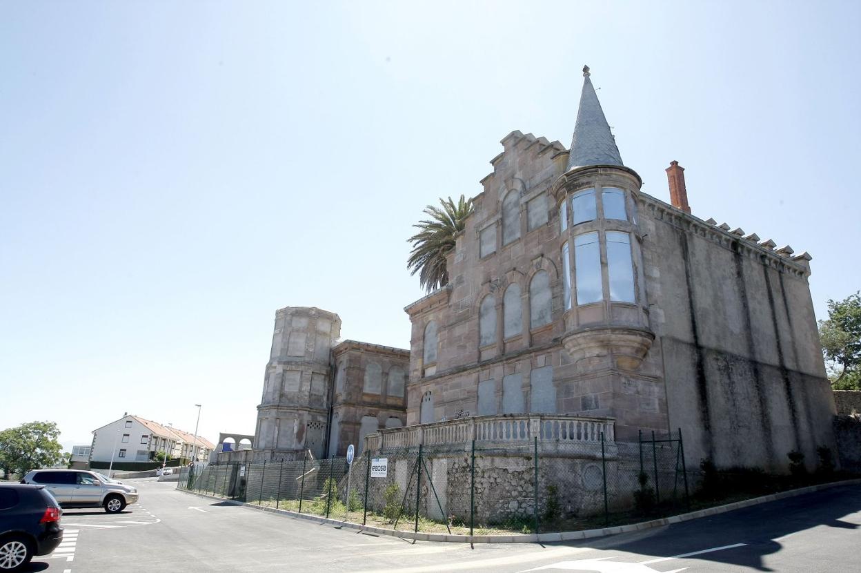 Imagen de la fachada vallada del edificio junto al aparcamiento.