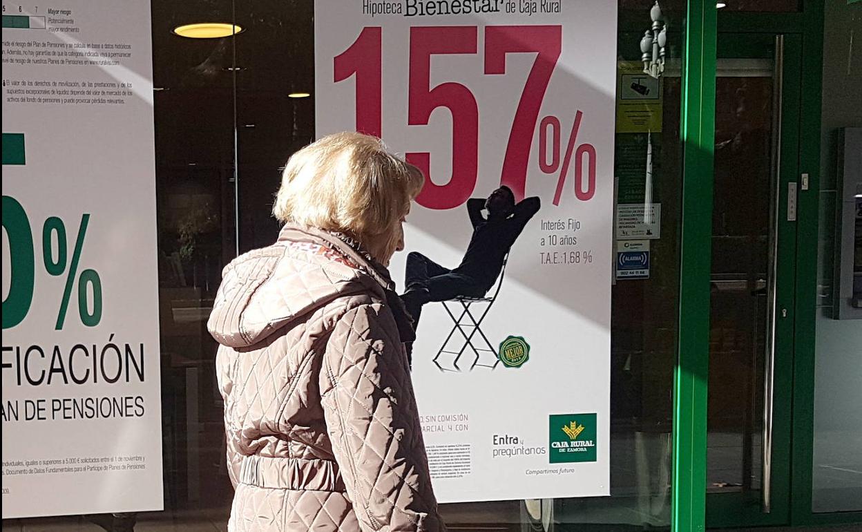 Una mujer frente a un escaparate de una oficina bancaria.